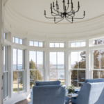 Chairs in large nook with domed ceiling, wrought iron chandelier, tall windows, stunning view of ocean