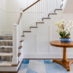 Stairwell with runner, side table with flowers, vase and rug